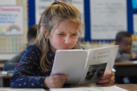 Little girl frustrated as she tries to read a book.